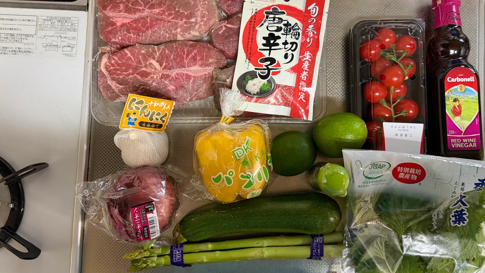 ミスジ肉と、にんにく・赤玉ねぎ・パプリカ・ライム・ミニトマト・ズッキーニ・アスパラ・大葉・赤ワインビネガーを並べたところ