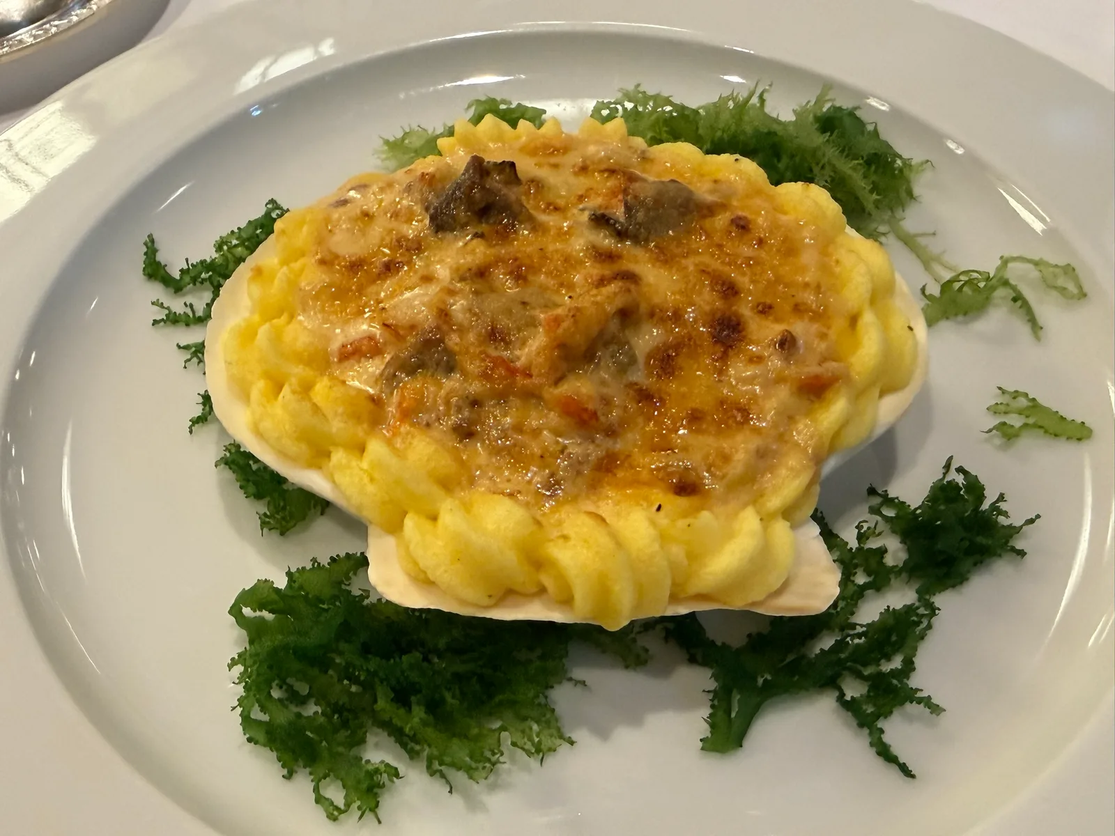貝殻の器のコキールグラタン。ポテトの縁取りにこんがり焼き色