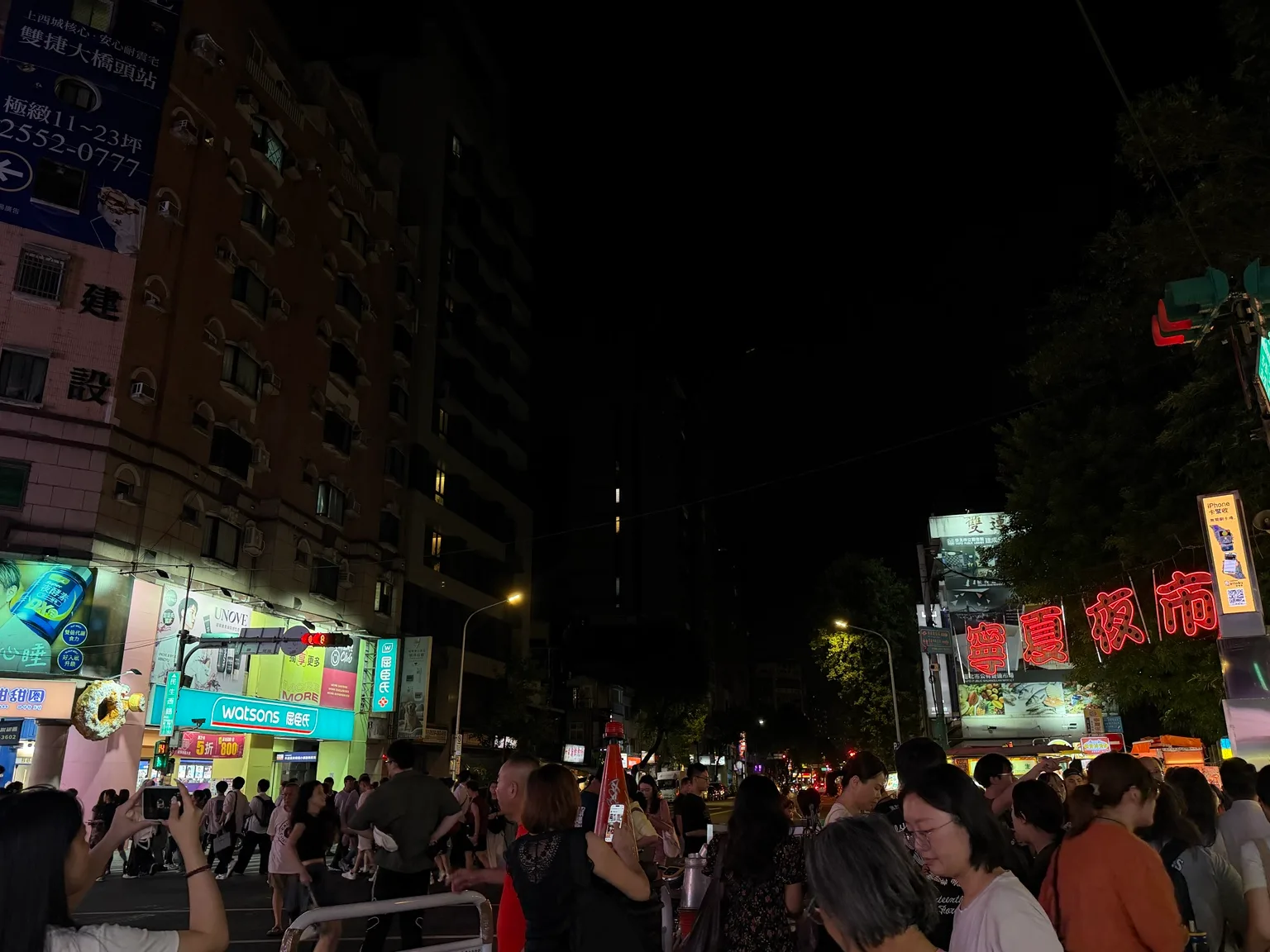 夜の交差点。人の流れと、右手に寧夏夜市のネオン