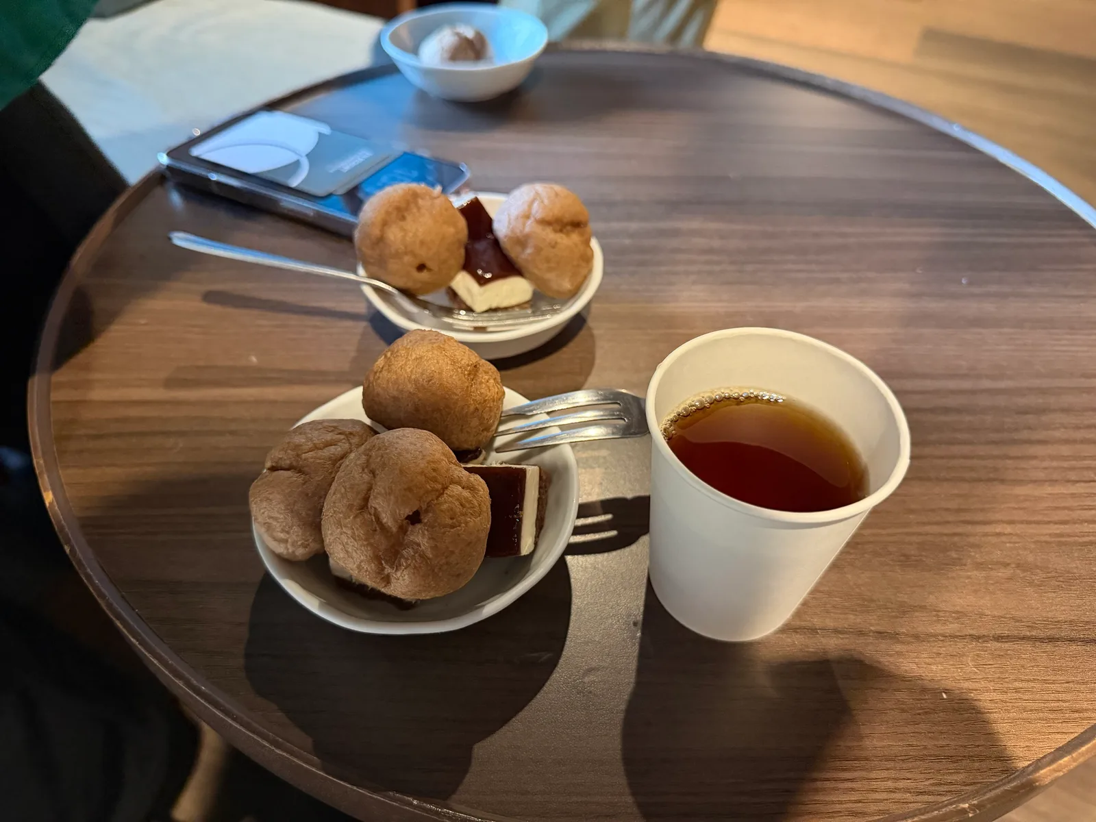 小皿に取ったティラミスとプチシュー、紙コップのコーヒー