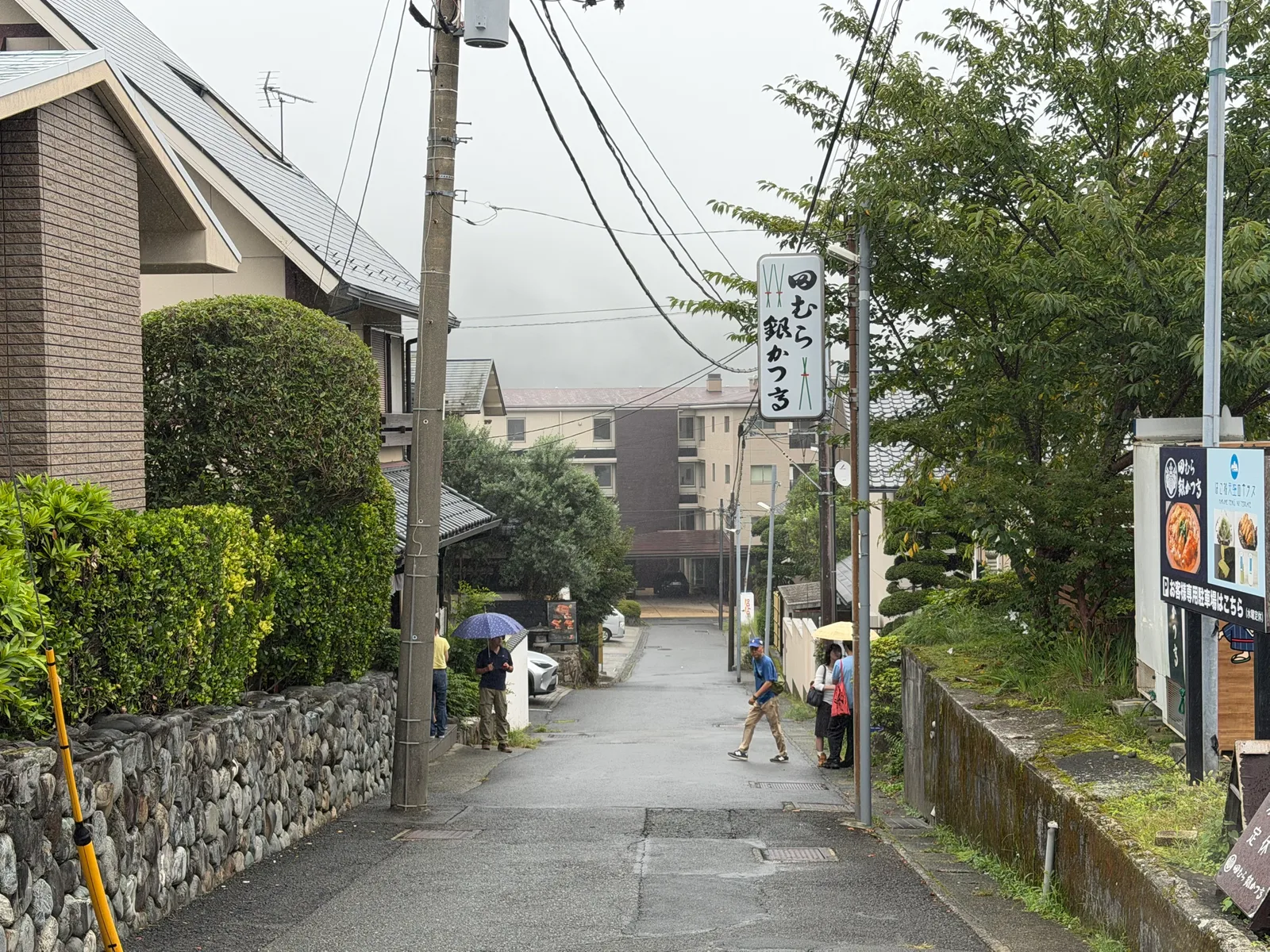 住宅街の坂道。「田むら 銀かつ亭」の白い看板が下がる