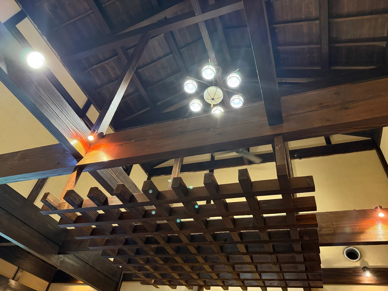 太い梁と格子の天井。丸い照明が下がる店内